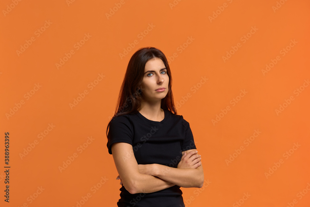 It is a big problem for me. Contemplative caucasian woman in black t-shirt keeps hands crossed over chest, ponders on how to solve situation, looking for solution. Isolated over an orange background. It is a big problem for me. Contemplative caucasian woman in black t-shirt keeps hands crossed over chest, ponders on how to solve situation, looking for solution. Isolated over an orange background.