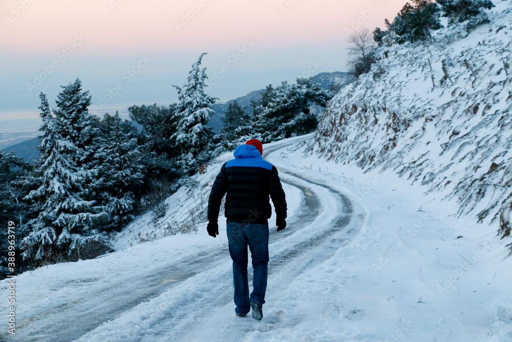 man taking a walk on a snowy mountain road.