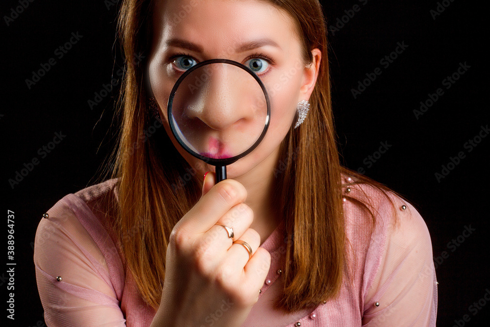 Blonde with long hair, magnifying her nose with a magnifying glass. Blonde with long hair, magnifying her nose with a magnifying glass.