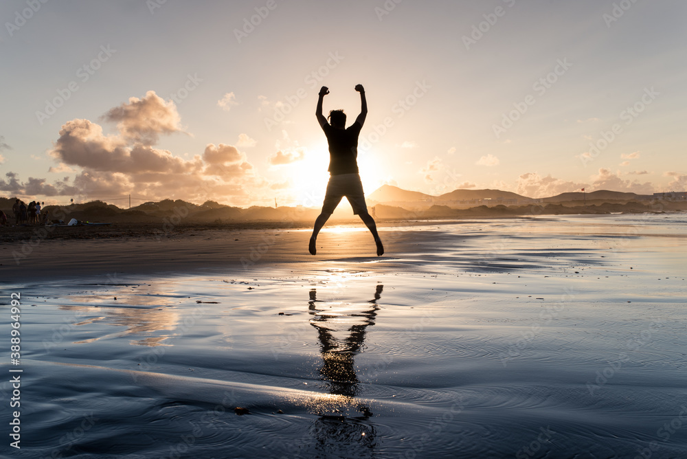 Happy man jumping on the beach with beautiful sunset. Succesful