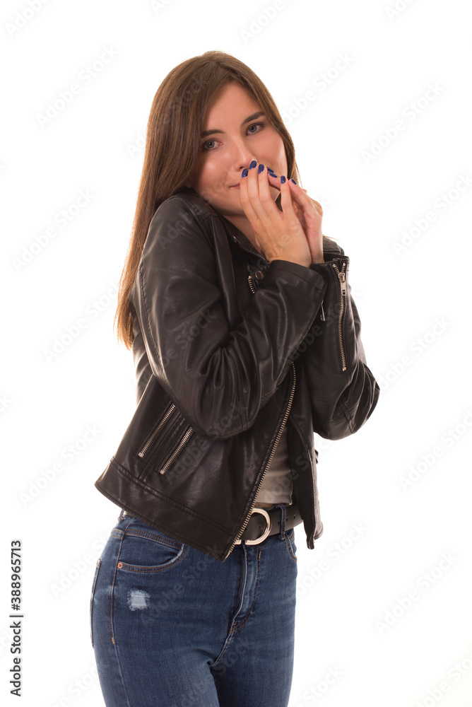 Shy girl stands on a white background and covers her face with her hand. Girl in a leather jacket poses at the camera and is shy. Shy girl stands on a white background and covers her face with her hand. Girl in a leather jacket poses at the camera and is shy.