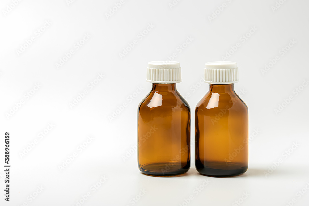 Glass containers for medicines on a white background. Two empty brown pharmaceutical bottles without labels