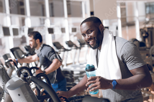Two men are engaged on treadmills in modern gym.