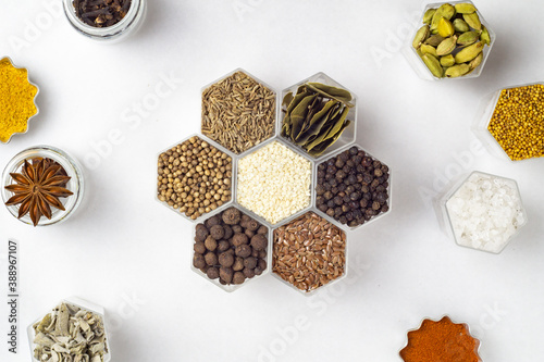 Spices in hexagonal jars on a white background