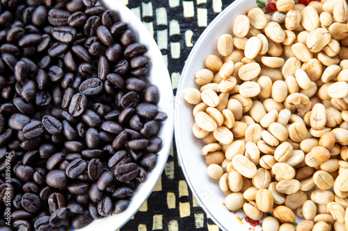 Dry group of black and white coffee bean in a white bowl.