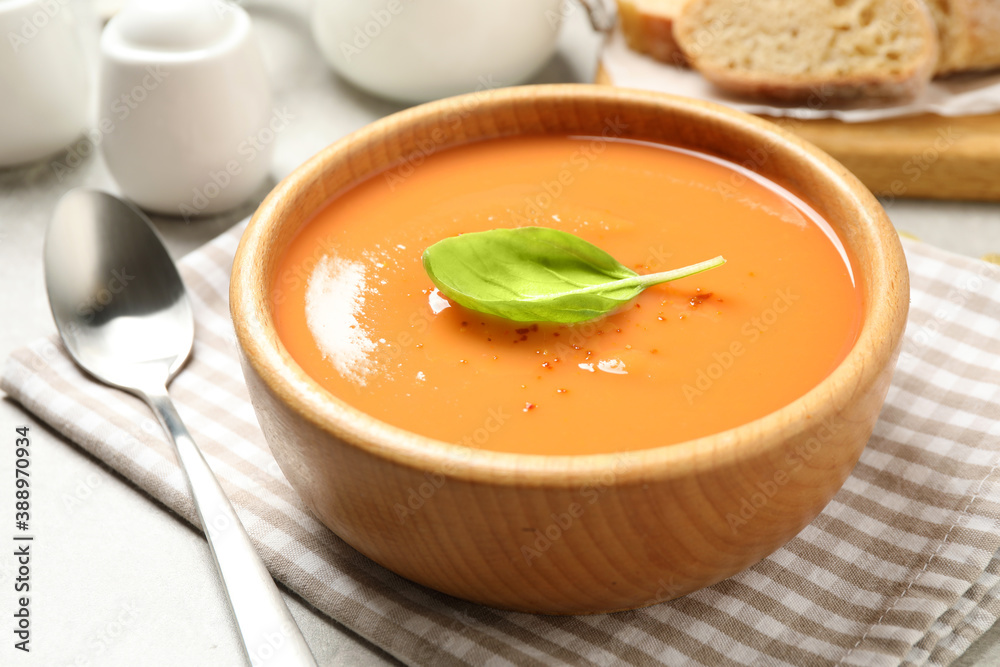Tasty creamy pumpkin soup with basil in bowl on table Tasty creamy pumpkin soup with basil in bowl on table