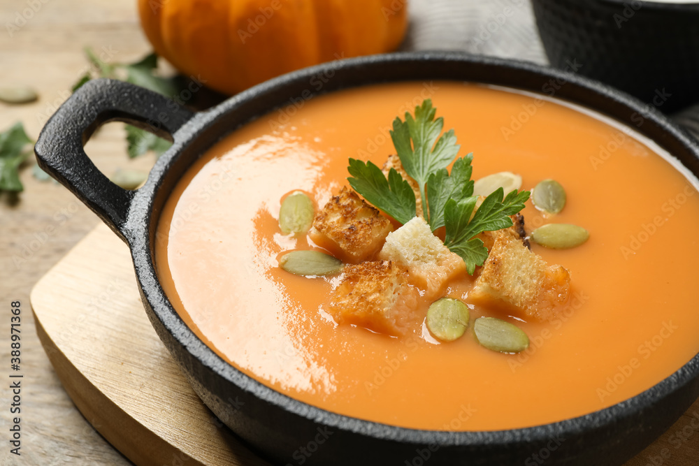 Tasty creamy pumpkin soup with croutons, seeds and parsley in bowl on table, closeup Tasty creamy pumpkin soup with croutons, seeds and parsley in bowl on table, closeup
