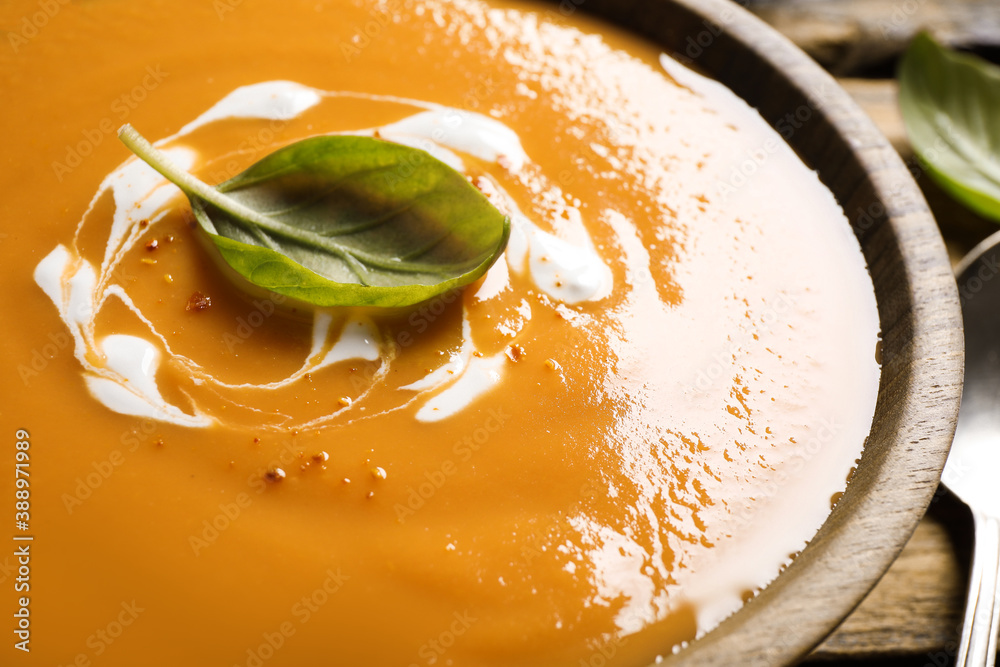 Tasty creamy pumpkin soup with basil in bowl, closeup
