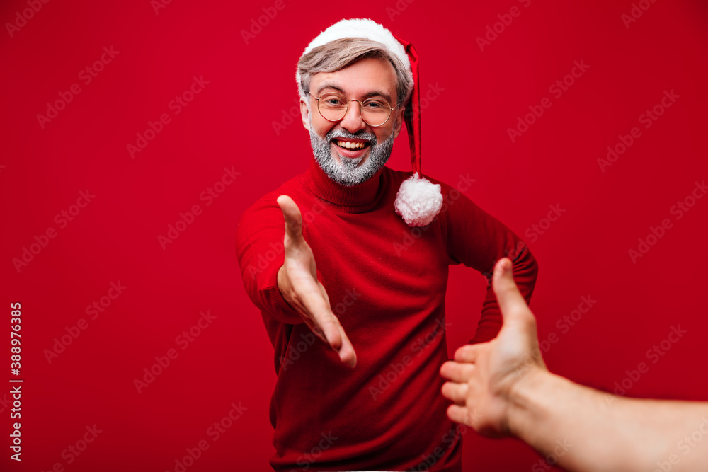 Excited old man posing with smile in christmas day. Studio photo of happy grey-haired grandpa in santa claus costume.