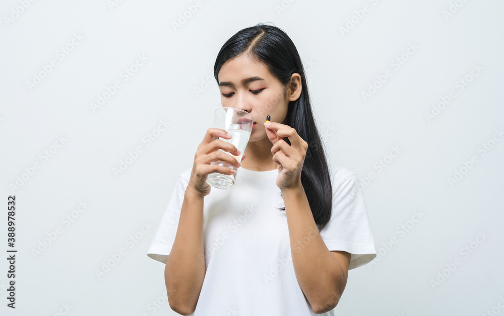 Happy Asian woman taking pill and holding glass of fresh water. Happy Asian woman taking pill and holding glass of fresh water.