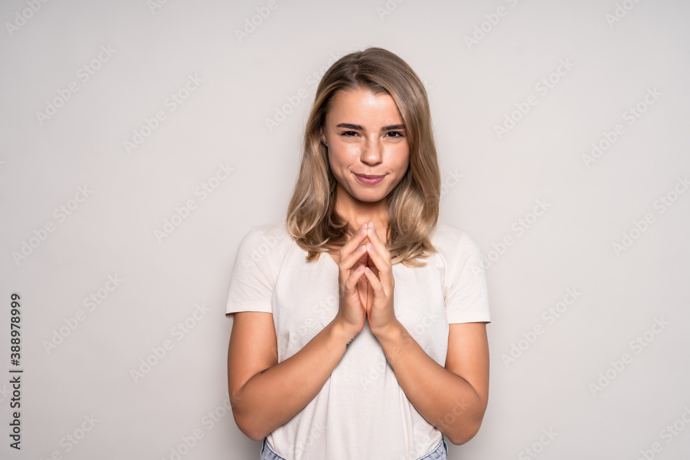 Portrait of sly woman looking with cunning eyes holding her hands together trying to ask something in sly manner. Cute female expressing her slyness in front of camera Portrait of sly woman looking with cunning eyes holding her hands together trying to ask something in sly manner. Cute female expressing her slyness in front of camera