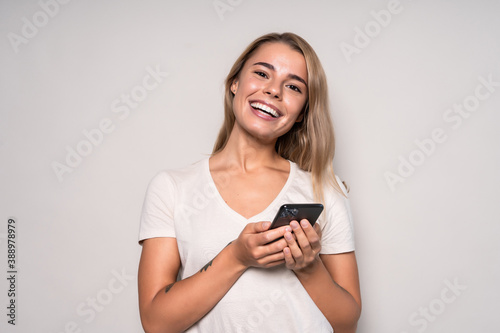 Portrait of a thoughtful young woman holding mobile phone and looking up at copy space isolated over white background