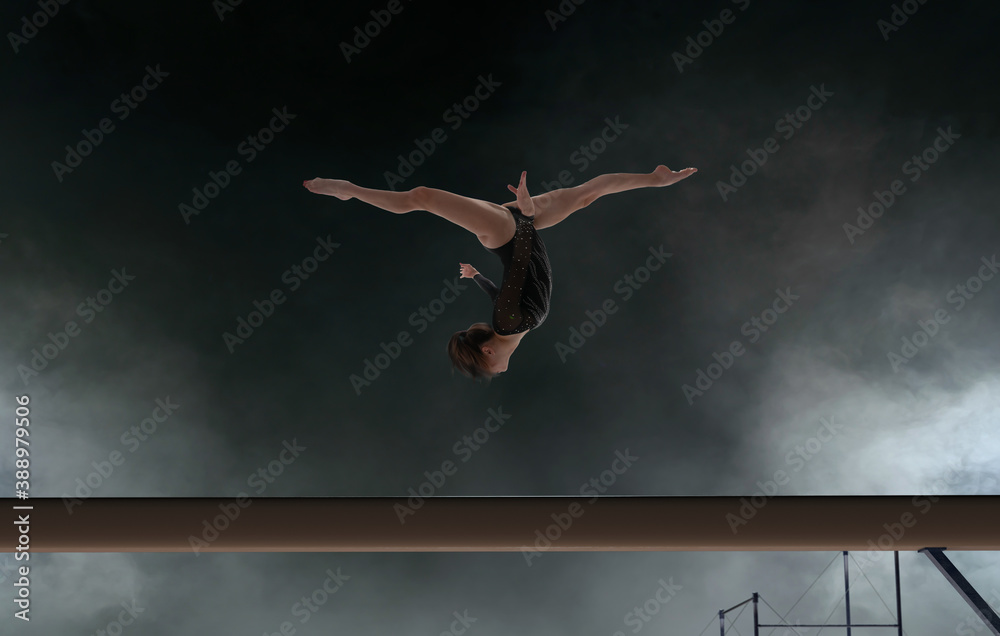 Female gymnast doing a complicated trick in a professional arena. Female gymnast doing a complicated trick in a professional arena.