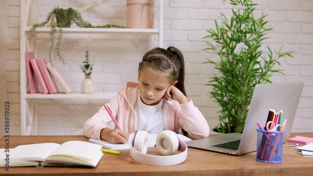 little child girl using laptop for doing school tasks at home and writing notes. online lesson at home little child girl using laptop for doing school tasks at home and writing notes. online lesson at home