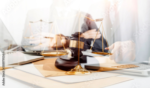 Business and lawyers discussing contract papers with brass scale on desk in office. Law, legal services, advice, justice and law concept picture with film grain effect