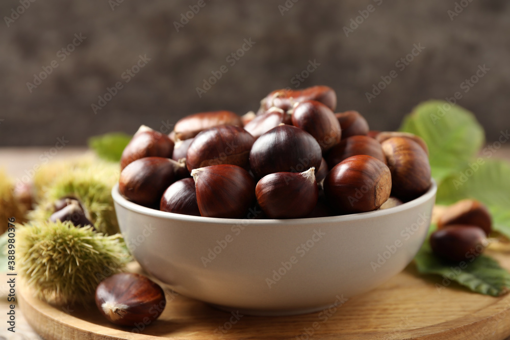 Fresh sweet edible chestnuts in bowl on wooden board Fresh sweet edible chestnuts in bowl on wooden board
