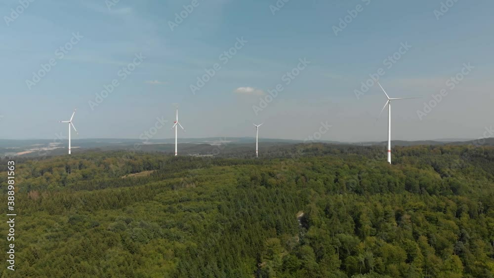 Aerial dolly shot of a cluster of wind turbines in the German countryside, bright blue sky day. Aerial dolly shot of a cluster of wind turbines in the German countryside, bright blue sky day.