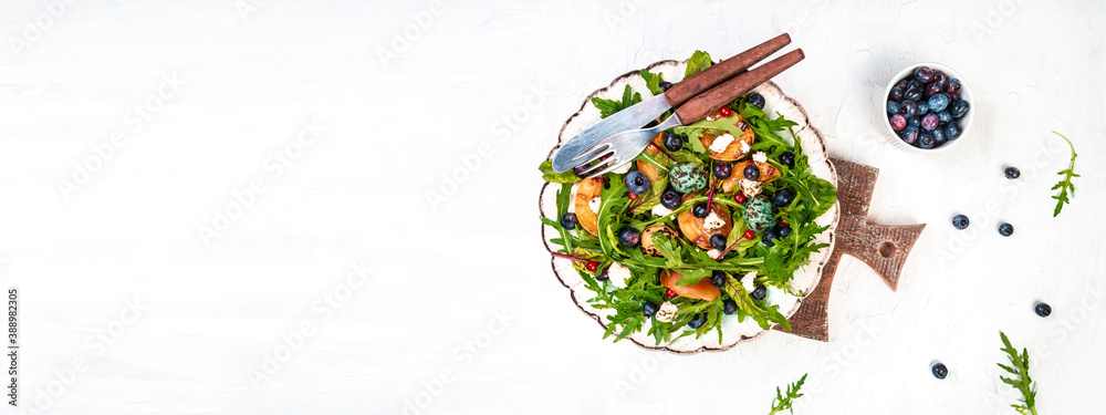 Easy recipe for summer salad with goat cheese, grilled apricots, arugula, berries, close-up on a plate wooden background, recipe top view