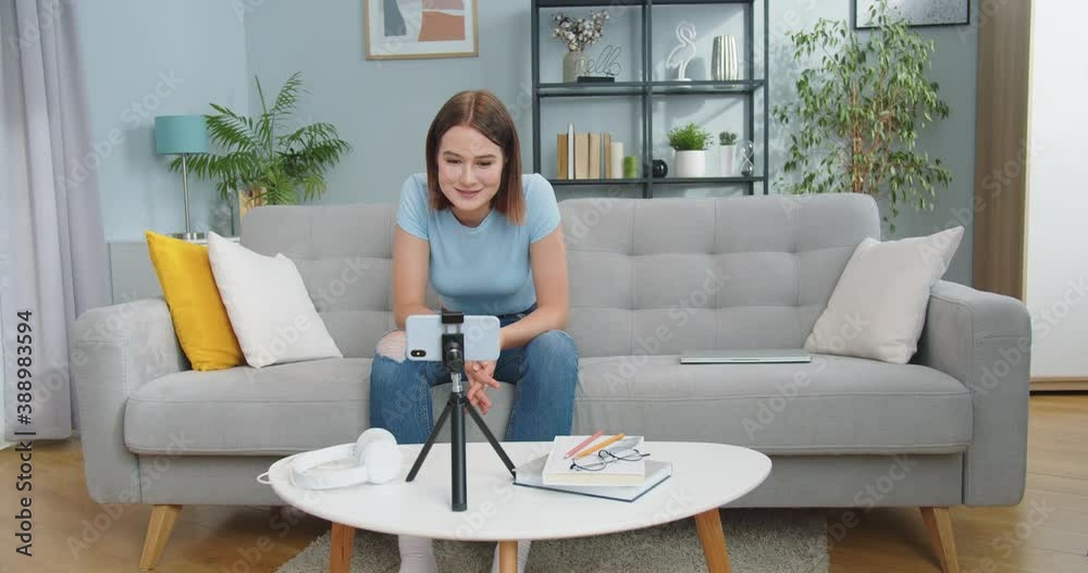 Charming young female calling friend while sitting on sofa in living room at home. Emotional Caucasian woman talking via video conference chat online. Internet, social media, delf-isolation concept. Charming young female calling friend while sitting on sofa in living room at home. Emotional Caucasian woman talking via video conference chat online. Internet, social media, delf-isolation concept.