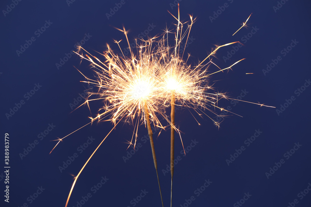 Bright burning sparkler on blue background, closeup