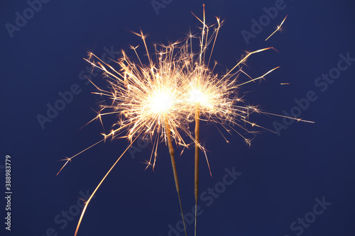 Bright burning sparkler on blue background  closeup