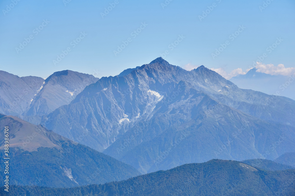 view from a height of mountain peaks with glaciers in a blue atmospheric haze