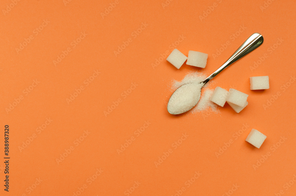 Fototapeta premium Top view of teaspoon and sugar on the orange surface.Empty space