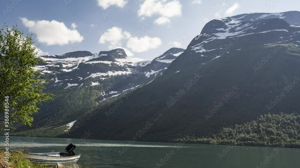 Boat Moored On The Lakeside At The Fjord During Winter With Rocky Mountain In The Background - motion time lapse Boat Moored On The Lakeside At The Fjord During Winter With Rocky Mountain In The Background - motion time lapse