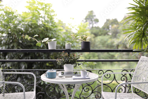Blue and white coffee cup with tablet and plant pot at balcony outdoor view 