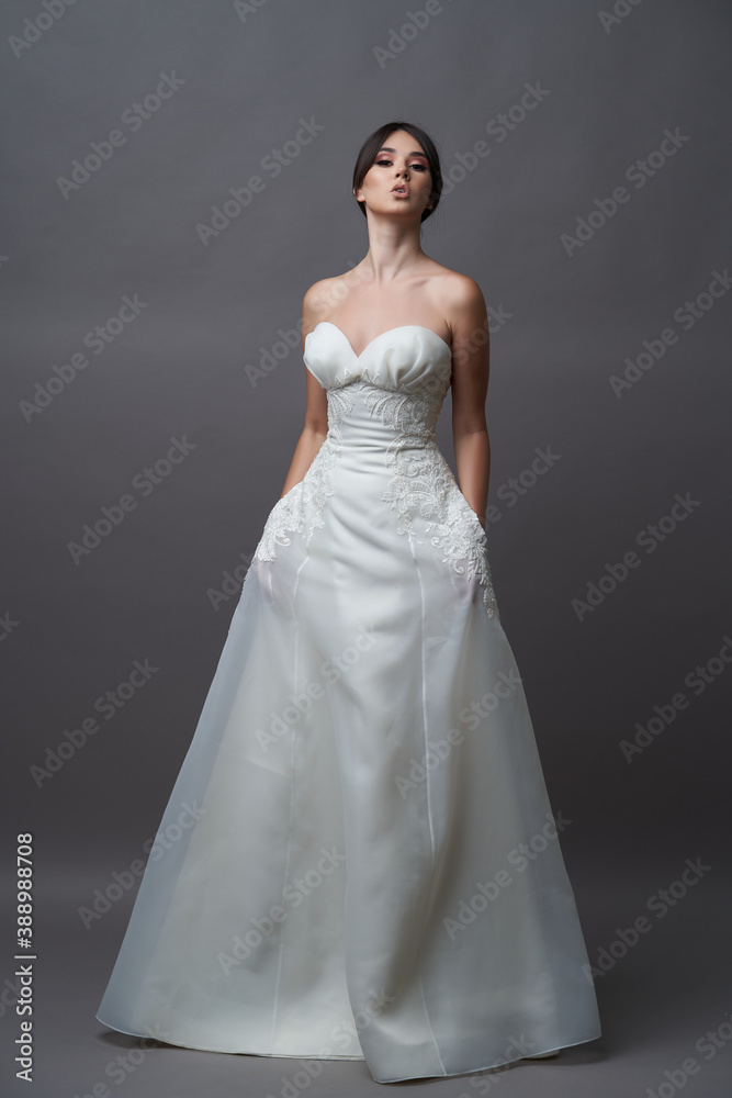 Beautiful bride in wedding dress posing on grey background with copy space.