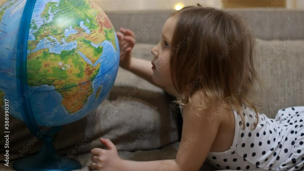 Baby girl studies geography and a map of the world. Child playing with globe. Baby girl studies geography and a map of the world. Child playing with globe.