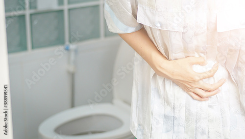 The woman stood in the bathroom in the toilet. With severe diarrhea Use both hands to hold on to the stomach, pain, twisting, torture.