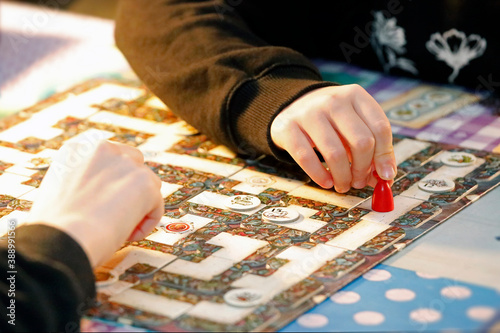 Board game labyrinth with child's hands, game figure and game dice.