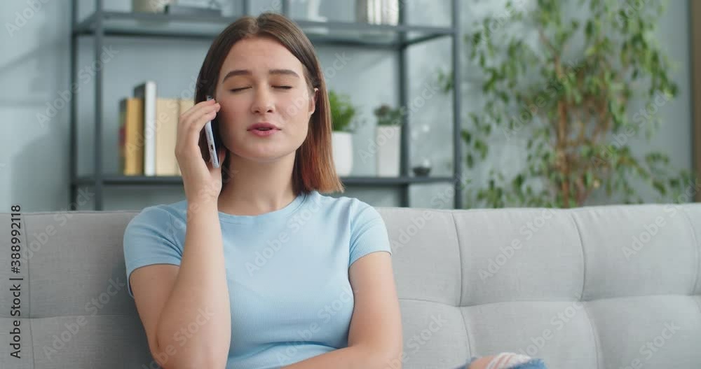 Portrait of good-looking Caucasian female calling friend while sitting on sofa. Attractive young woman talking to friend in living room at home. Technology, gadgets, communication concept. Portrait of good-looking Caucasian female calling friend while sitting on sofa. Attractive young woman talking to friend in living room at home. Technology, gadgets, communication concept.