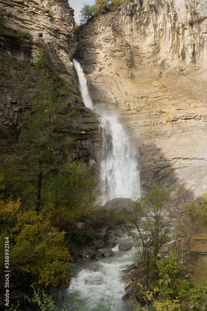 Upright Zoom photography of Cascada de Sorrosal (Sorrosal waterfall) with yellow autumn trees in Broto ,Spain 