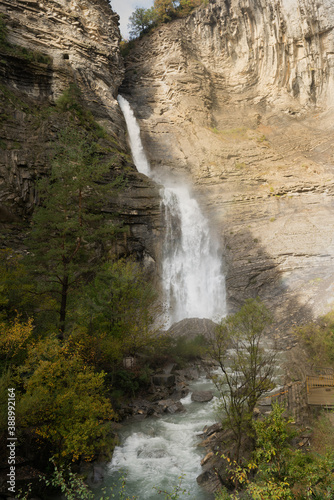 Upright Zoom photography of Cascada de Sorrosal (Sorrosal waterfall) with yellow autumn trees in Broto ,Spain 