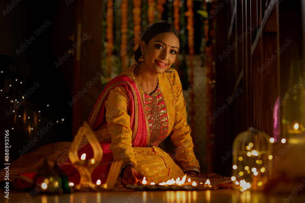 PORTRAIT OF A WOMAN SITTING WITH DIYAS AND SMILING PORTRAIT OF A WOMAN SITTING WITH DIYAS AND SMILING