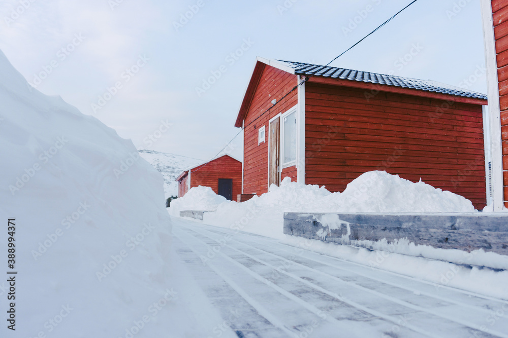 traditional red Board houses in the far North and cleared wooden decking from snow on a frosty day