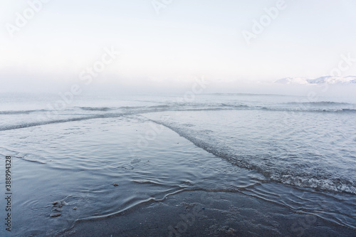 the water freezes and covers the sand with ice and snow on the seashore during the winter frost