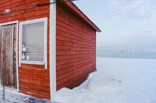 red traditional wooden houses in the North surrounded by snow on a frosty day