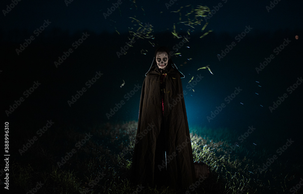 Woman stands in Halloween costume of death against dark sky. Woman stands in Halloween costume of death against dark sky.