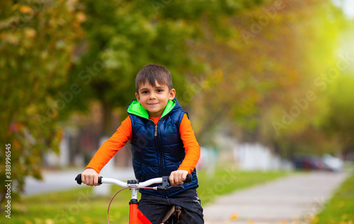 Sunny autumn day. Boy on a bike in a city park. The concept of relaxation and fun spending time. Photo with lots of white space