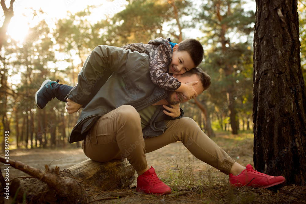 Piggyback. Father and son walking and having fun in autumn forest, look happy and sincere. Laughting, playing, having good time together. Concept of family, happiness, holidays, childhood, lifestyle. Piggyback. Father and son walking and having fun in autumn forest, look happy and sincere. Laughting, playing, having good time together. Concept of family, happiness, holidays, childhood, lifestyle.