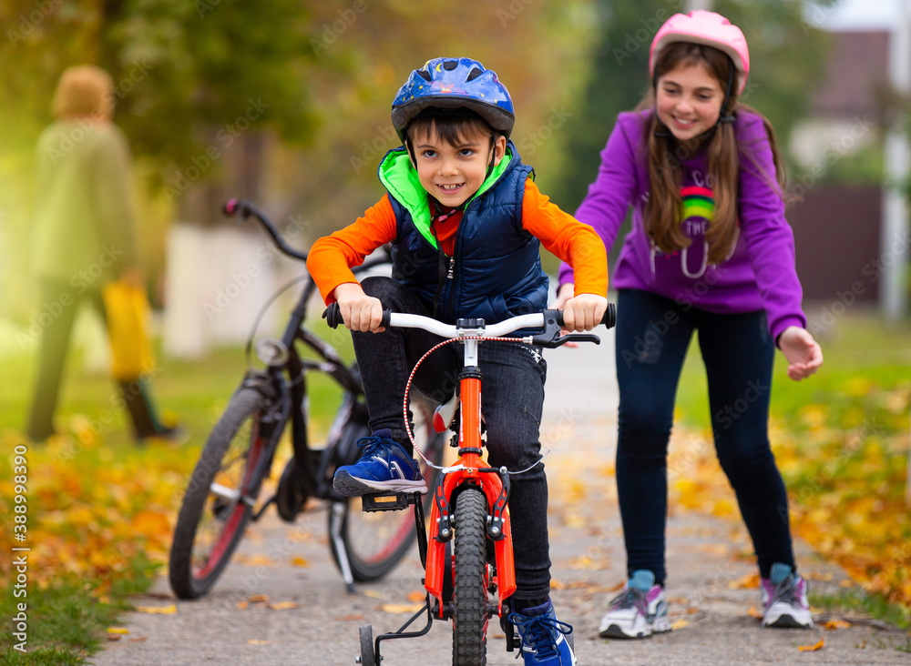 Autumn day. Sister teaches her little brother to ride a bike and rejoices at his success. Family and healthy lifestyle