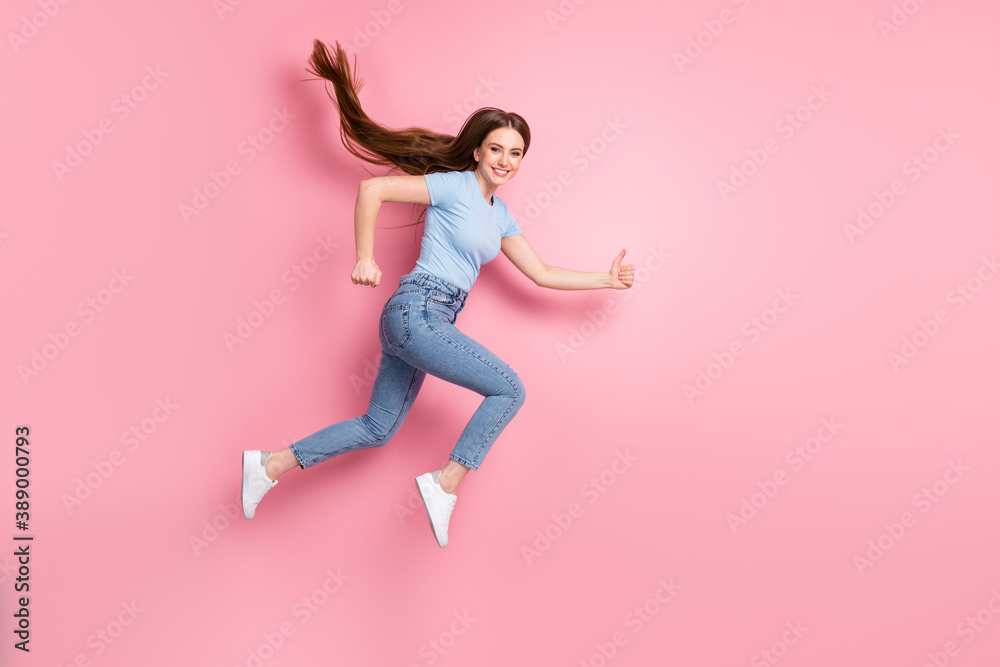 Photo portrait of running jumping up girl showing thumbs up isolated on pastel pink colored background