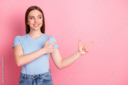 Photo portrait of woman pointing to fingers looking to side isolated on pastel pink colored background