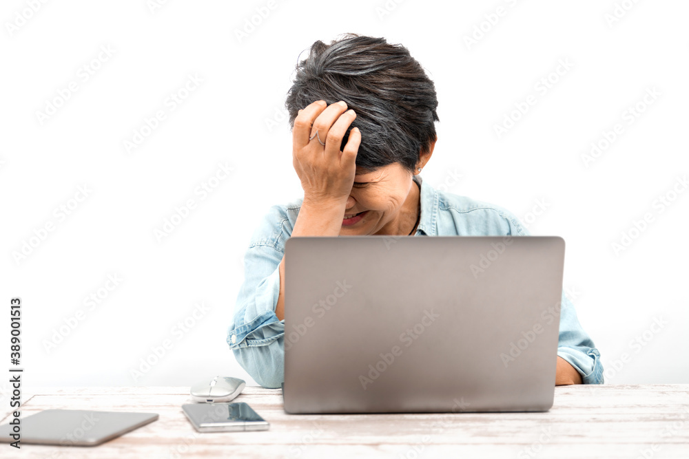 A senior Asian businesswoman is upset or has some trouble while working on a laptop in the office. White background. The concept of learning the elderly to computer knowledge or internet skill A senior Asian businesswoman is upset or has some trouble while working on a laptop in the office. White background. The concept of learning the elderly to computer knowledge or internet skill