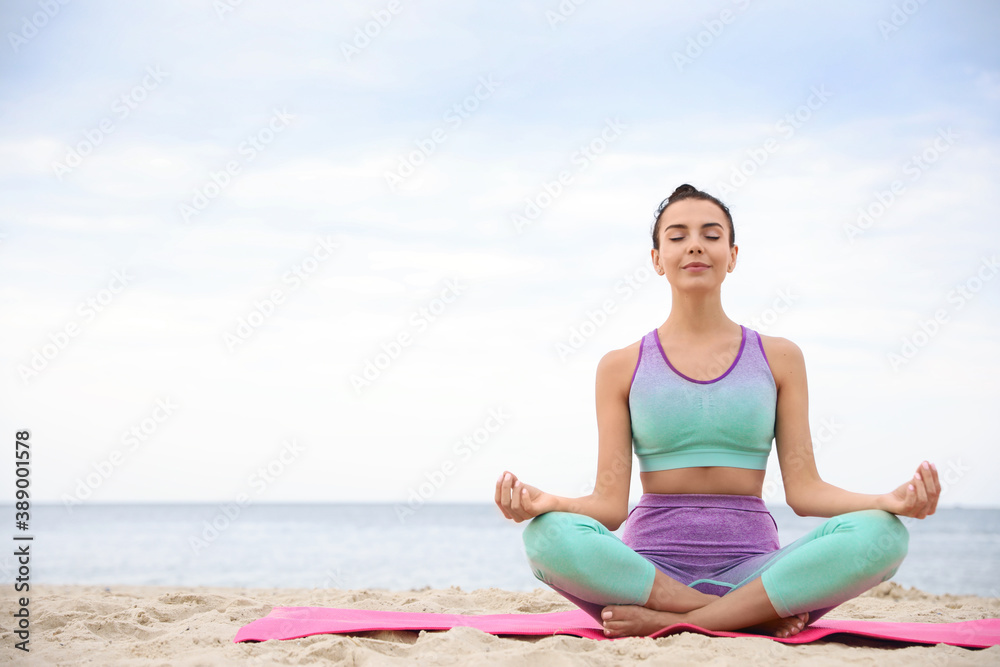Young woman practicing yoga on beach, space for text. Body training
