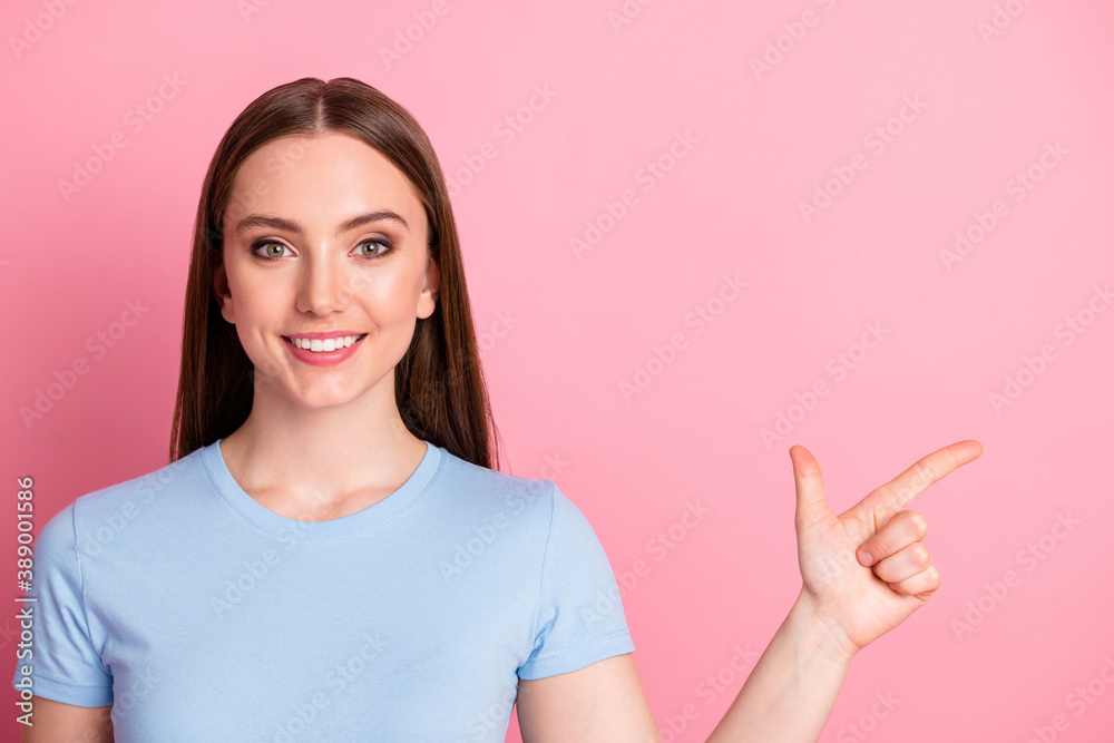 Photo portrait of woman pointing one finger to side isolated on pastel pink colored background Photo portrait of woman pointing one finger to side isolated on pastel pink colored background