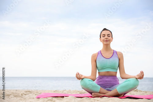 Young woman practicing yoga on beach  space for text. Body training